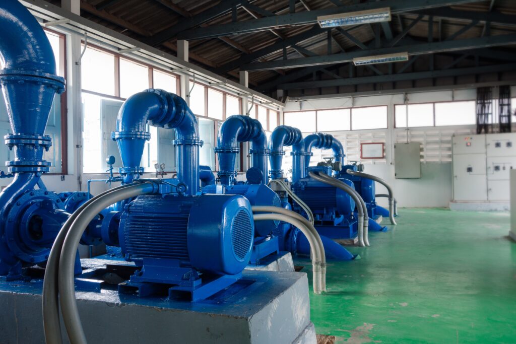 A row of large blue industrial water pumps with electric motors installed