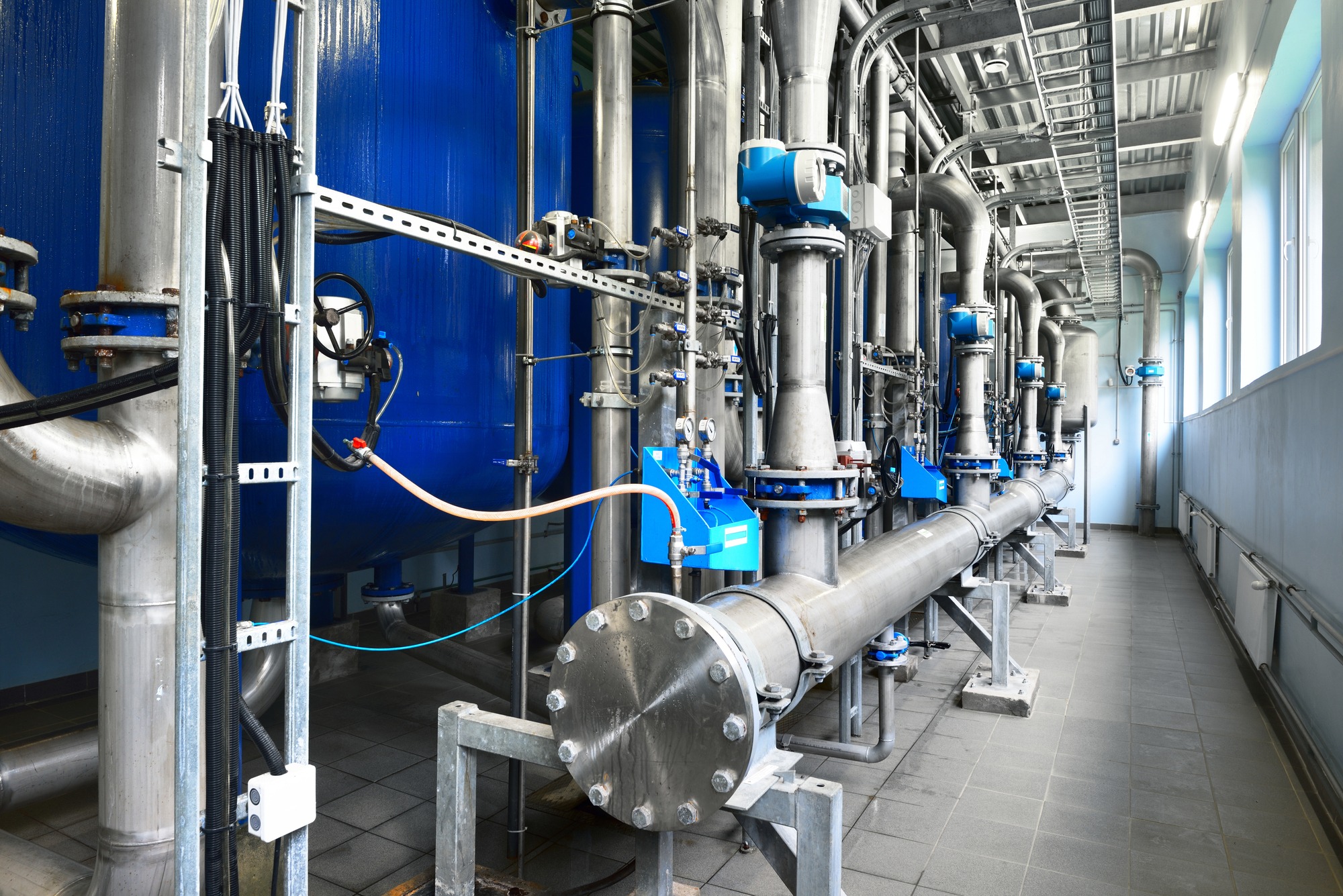 Shiny steel metal pipes and blue pupms and valves.